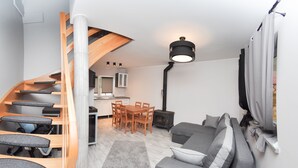 A modern interior with a wooden staircase, a dining area, a sofa, and a black lamp.