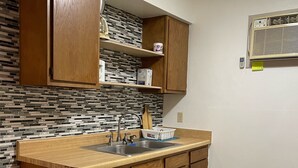 A kitchen with wooden cabinets, a tiled backsplash, a sink, and a built-in stove. - 1326-#9 Comfy studio in downtown  (San Antonio)