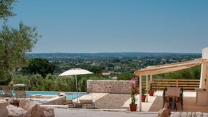 Un patio con piscina, muebles de exterior y vistas del paisaje.