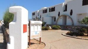 A white building with a sign reading "ES BRUCIS" and a stone wall. - Villas es Brucs - 5 - 2 (Cala Morell)