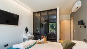 A modern hotel room with a bed, a vanity with a mirror, a tray with breakfast items, and a sliding door leading to a balcony.
