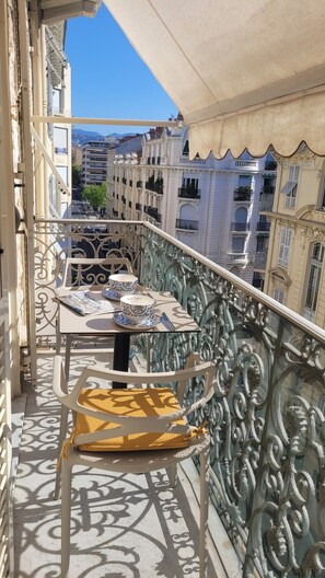 A balcony with a table set for two, featuring a patterned tablecloth and matching cups. - Charming Apartment in the Carré d'Or/Musiciens neighborhood, 5 minutes from the beach, Wi-Fi (Nice)
