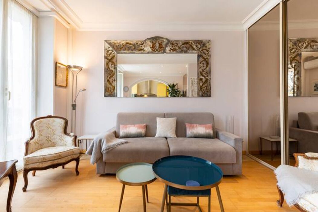A living room with a sofa, two side tables, a chair, and a large mirror.
