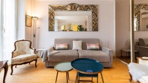 A living room with a sofa, two side tables, a chair, and a large mirror. - Charming flat Carré d'Or/Musiciens, 5 min away from the beach, WIFI (Nice)