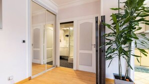 A hallway with a potted plant, a door leading to a bathroom, and a mirror reflecting the interior. - Charming flat Carré d'Or/Musiciens, 5 min away from the beach, WIFI (Nice)