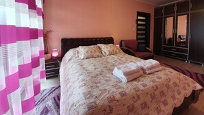 Ein Schlafzimmer mit Bett, Nachttisch, Stuhl, Kleiderschrank und Spiegel.