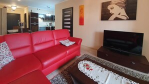 Ein Wohnzimmer mit einem roten Sofa, einem Fernseher und einem dekorativen Tisch.