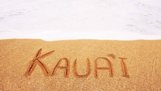 A beach with the word "Kauai" written in the sand.