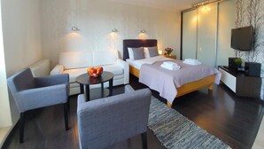 Ein modernes Hotelzimmer mit Bett, Sofa, kleinem Tisch und Fernseher.