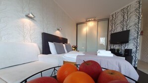 Ein modernes Hotelzimmer mit Bett, Sofa, Fernseher und Obstschale.