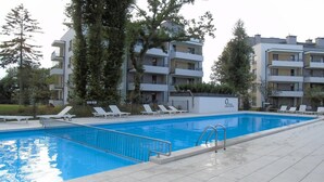 A swimming pool with lounge chairs, surrounded by apartment buildings. - Kap Ustronie Morskie - 365PAM (Ustronie Morskie)