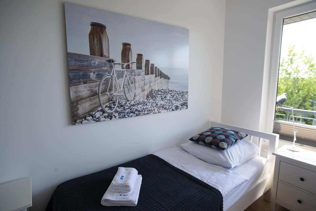 Une chambre à coucher avec un lit, une fenêtre et un tableau représentant un vélo accroché à une clôture en bois.