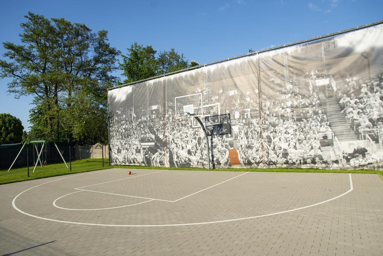 An outdoor basketball court with a mural on the wall.