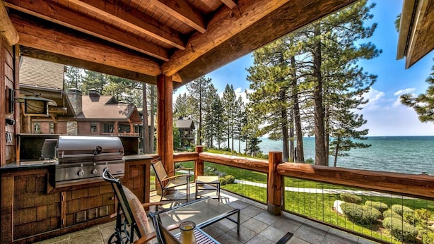 A wooden deck with a grill and seating area overlooking a lake and forest. - Exclusive Lakefront Luxury by Heavenly, Hot Tub | PEAK SS14 (South Lake Tahoe)