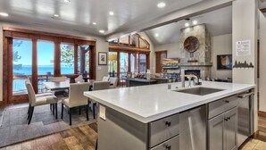 A modern kitchen with a large island, stainless steel appliances, and a stone fireplace. - Exclusive Lakefront Luxury by Heavenly, Hot Tub | PEAK SS14 (South Lake Tahoe)