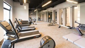 A gym with treadmills, a rowing machine, and weightlifting equipment.
