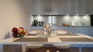 A modern kitchen with grey cabinets, a dining table with placemats, and a fruit bowl on the left.