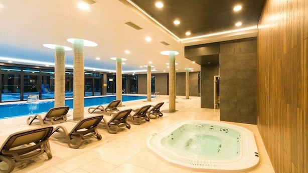 A spa area with a hot tub, lounge chairs, and a pool.
