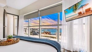 Ein Hotelzimmer mit einem großen Bett, einem Fernseher und Blick auf das Meer.