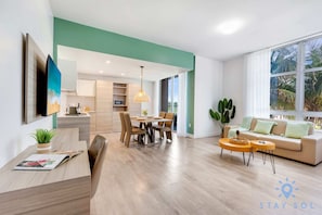 Relax in this stylish living space with a dining area, sofa, and large window offering a view of the surrounding greenery.