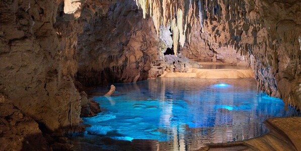 A natural cave with a pool of water and a person swimming.