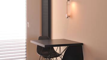 Un comedor moderno con una mesa, sillas, un radiador y una lámpara fijada a la pared.