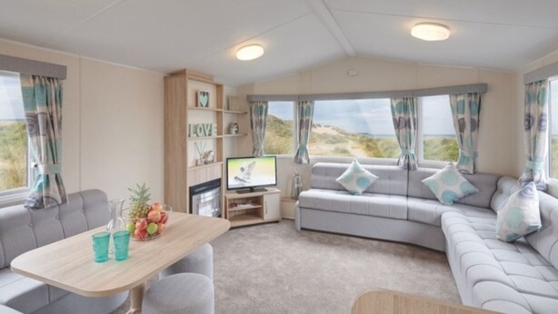 A cozy RV interior with a sofa, a dining table, and a TV. - Caravan - Sleeps6-pet Friendly-parking Available (Skegness)