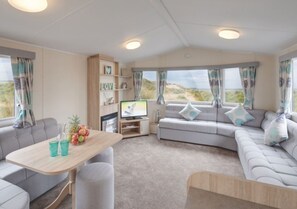 A cozy RV interior with a sofa, a dining table, and a TV. - Caravan - Sleeps6-pet Friendly-parking Available (Skegness)