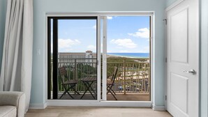 A room with a large sliding glass door leading to a balcony with a view of the beach and ocean. - Gulf Views ~ Studio ~ Resort Pool (Miramar Beach)