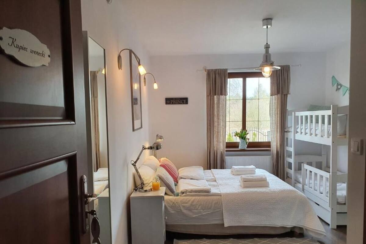 A bedroom with a bed, bedside table, lamp, and a crib.