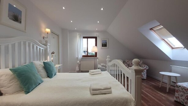 A bedroom with a large bed, a skylight, a view of the outdoors, and a small table. - Apartamenty Morskie Historie - 365PAM (Kolobrzeg)