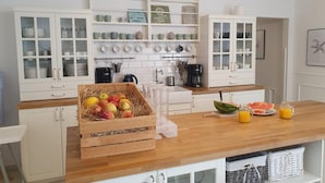 A kitchen with white cabinets, a wooden countertop, and various kitchen appliances. - Apartamenty Morskie Historie - 365PAM (Kolobrzeg)