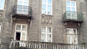 A multi-story building with a central entrance, multiple windows, and balconies.