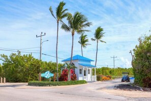 A small, single-story building with a blue roof, surrounded by palm trees and greenery, with a sign reading "Ocean Pointe". - Snorkel & Dive Legendary Coral Reefs - Then Relax Poolside with a Drink! (Tavernier)