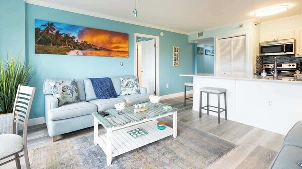 A living room with a sofa, coffee table, and a painting on the wall. - Snorkel & Dive Legendary Coral Reefs - Then Relax Poolside with a Drink! (Tavernier)