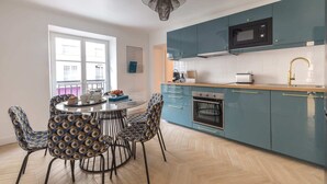 Una cocina moderna con gabinetes color aguamarina, un microondas, un tostador y un lavamanos con grifo dorado.