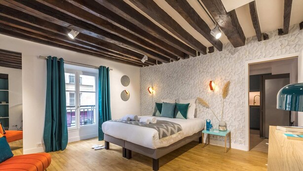 Un dormitorio moderno con techo de madera, una cama grande, una mesita de noche, un escritorio y vistas al exterior.