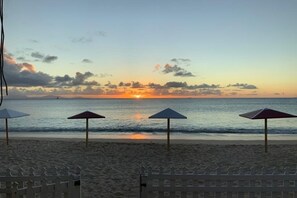 A beach with umbrellas and a fence.