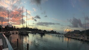 A marina with boats docked at wooden piers, surrounded by hills and a sunset sky. - Jolly Harbour, 3 bedroom villa, pool, close to beach and all amenities. (Jolly Harbour)