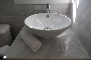 A bathroom with a white sink, a toilet, and a towel on the counter.