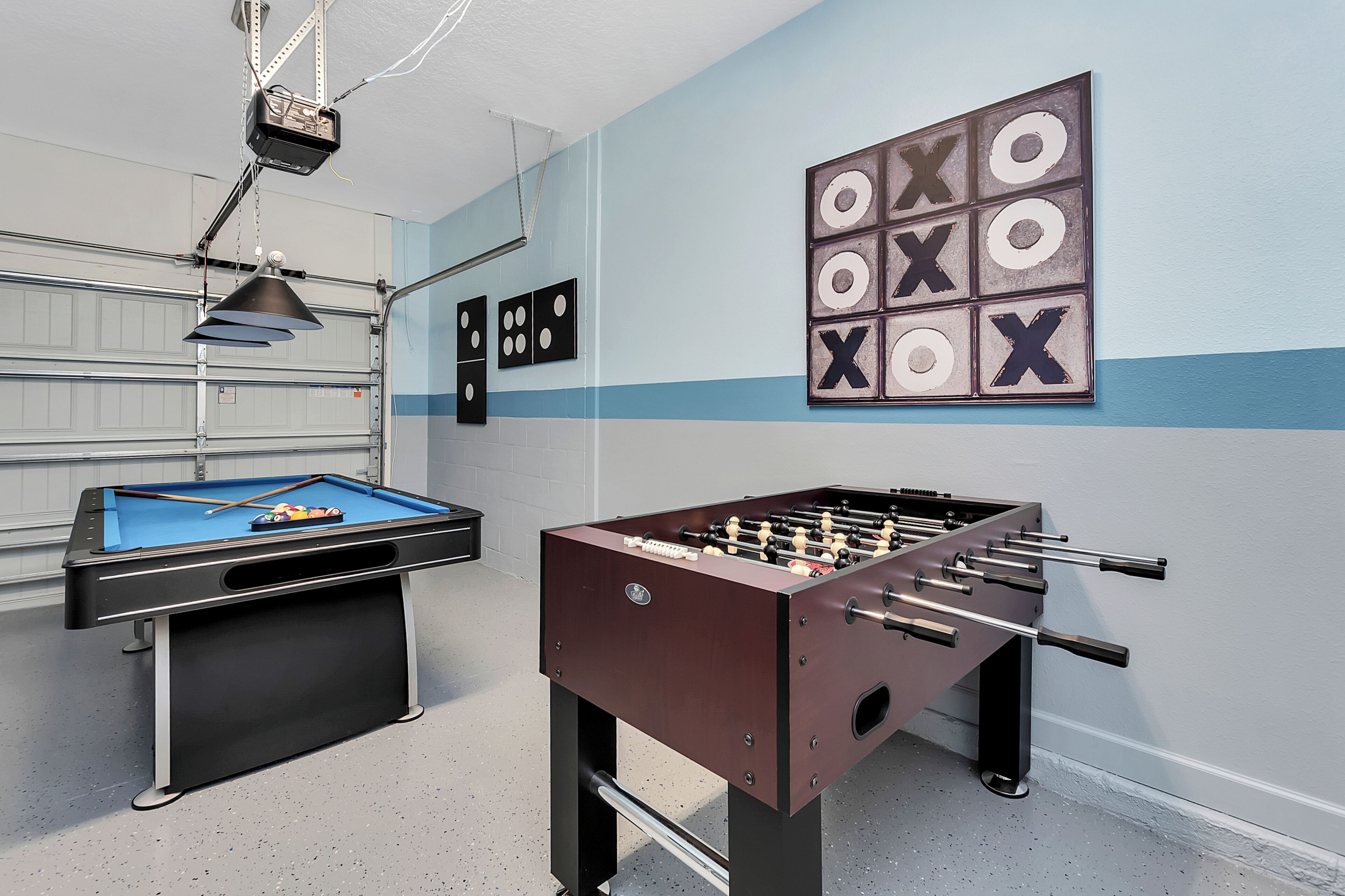 A room with a pool table, foosball table, and a dartboard.