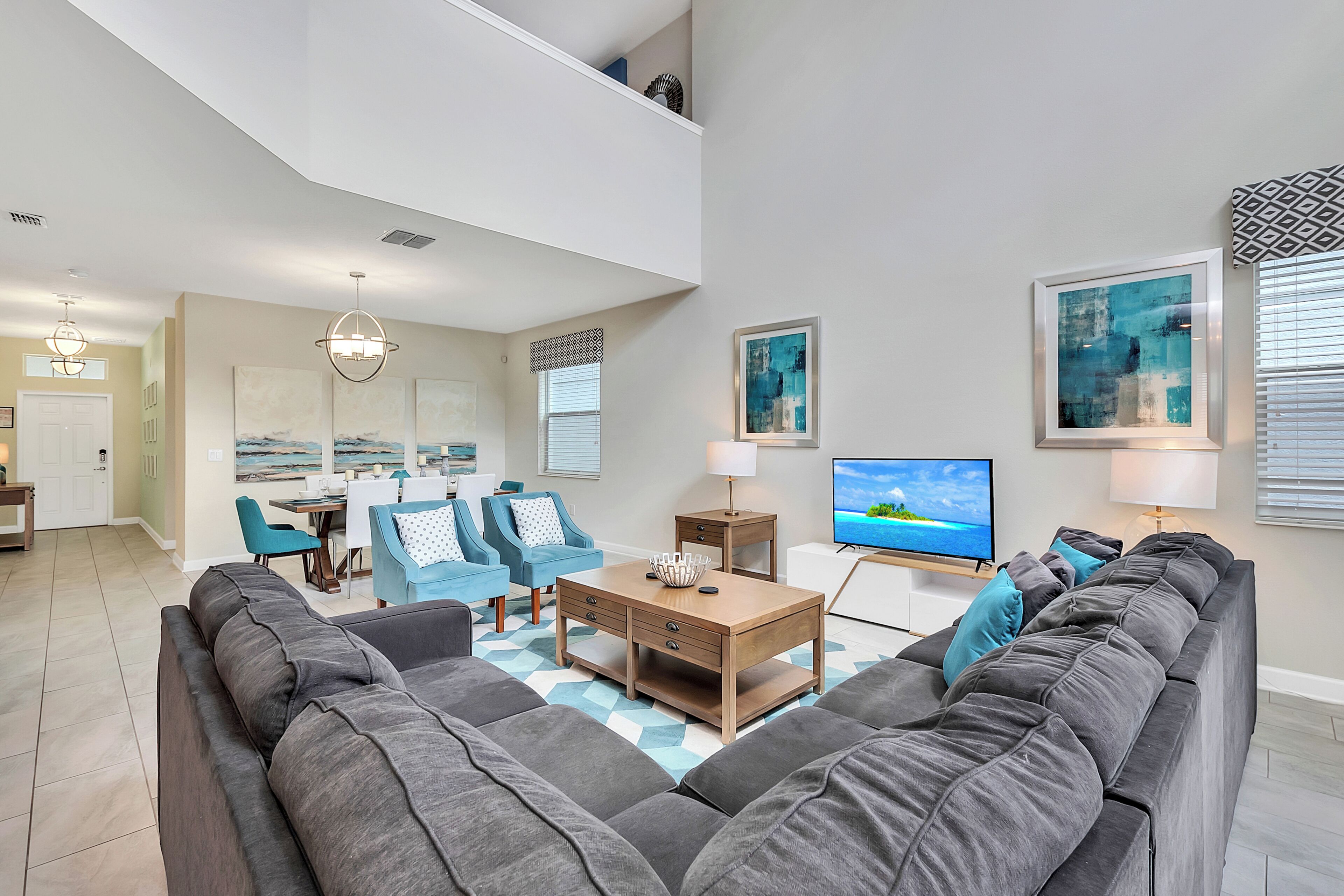 Een moderne woonkamer met een hoekbank, een salontafel en een eethoek met blauwe stoelen.