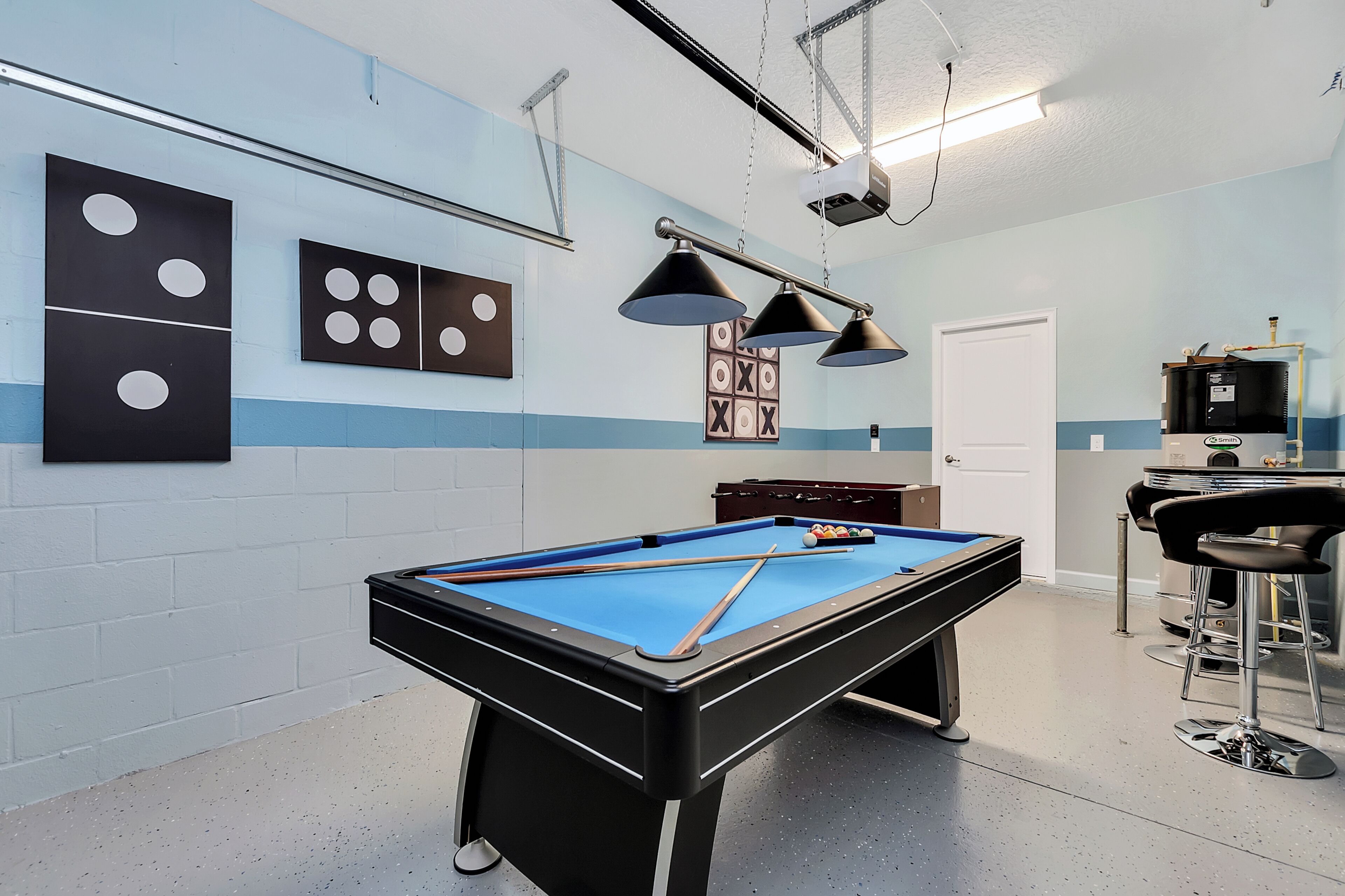 A pool table in a room with a blue and white color scheme, a bar area with stools, and a water heater.