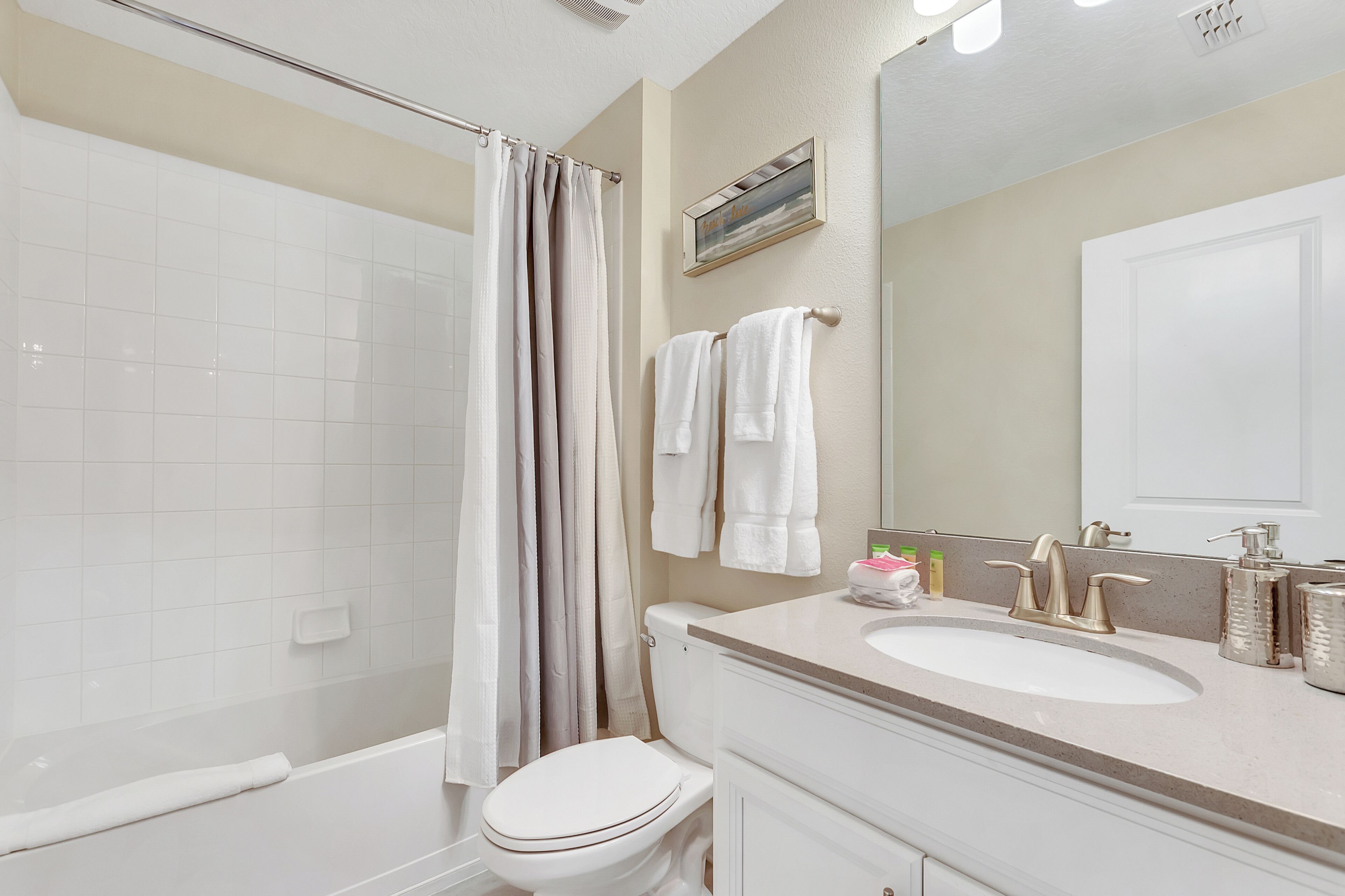 A bathroom with a shower, toilet, sink, and mirror.