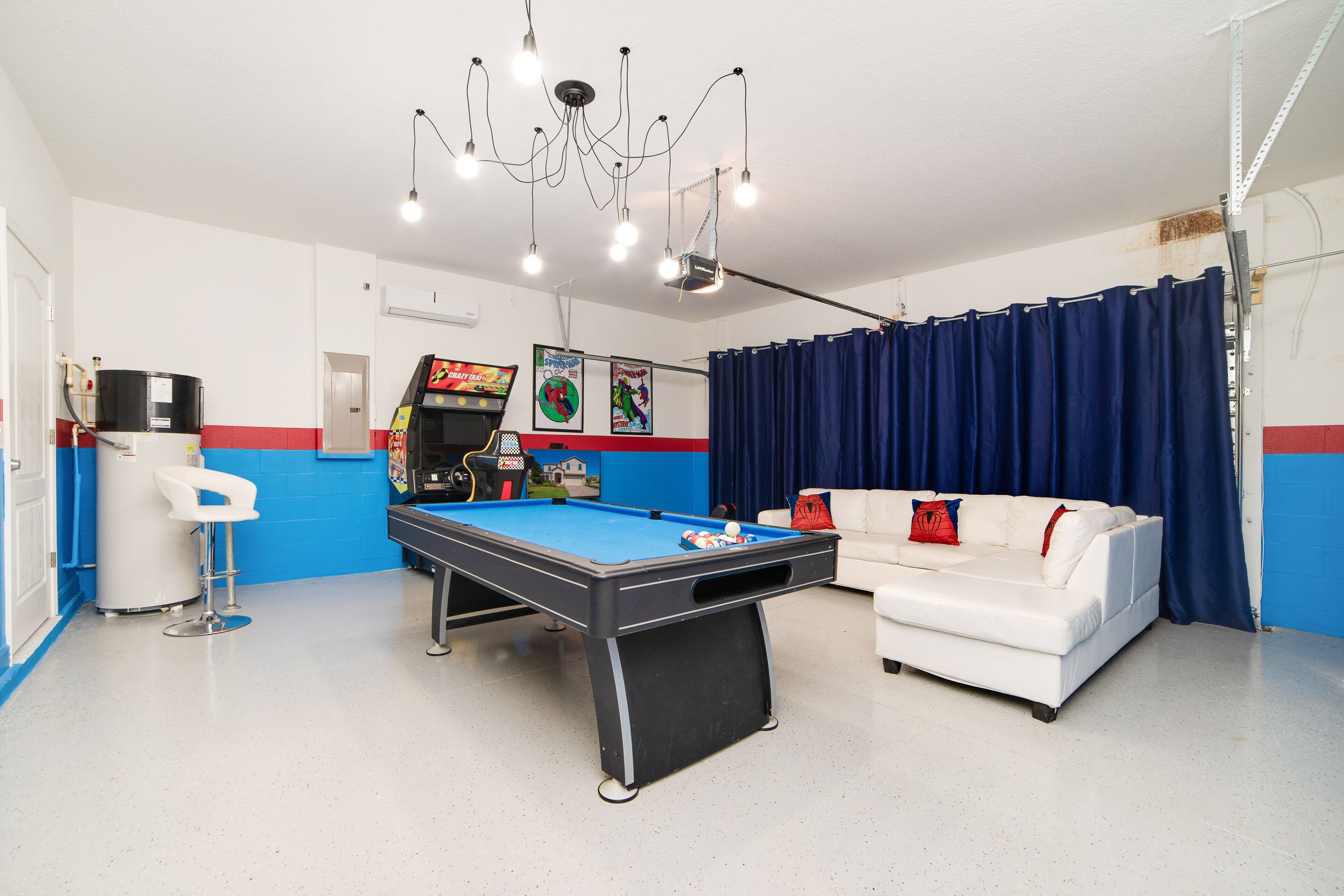 A pool table in a room with a white and blue color scheme, a white sofa, and a chandelier.