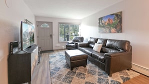 A living room with a leather sofa, a flat-screen TV, and a painting on the wall. - Gold Creek Condo: Downtown, Amazing Views (Breckenridge)