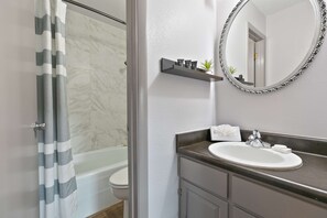 A bathroom with a bathtub, a sink, and a mirror.