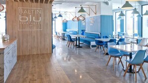 Un interior de restaurante moderno con detalles de madera, asientos azules e iluminación colgante.