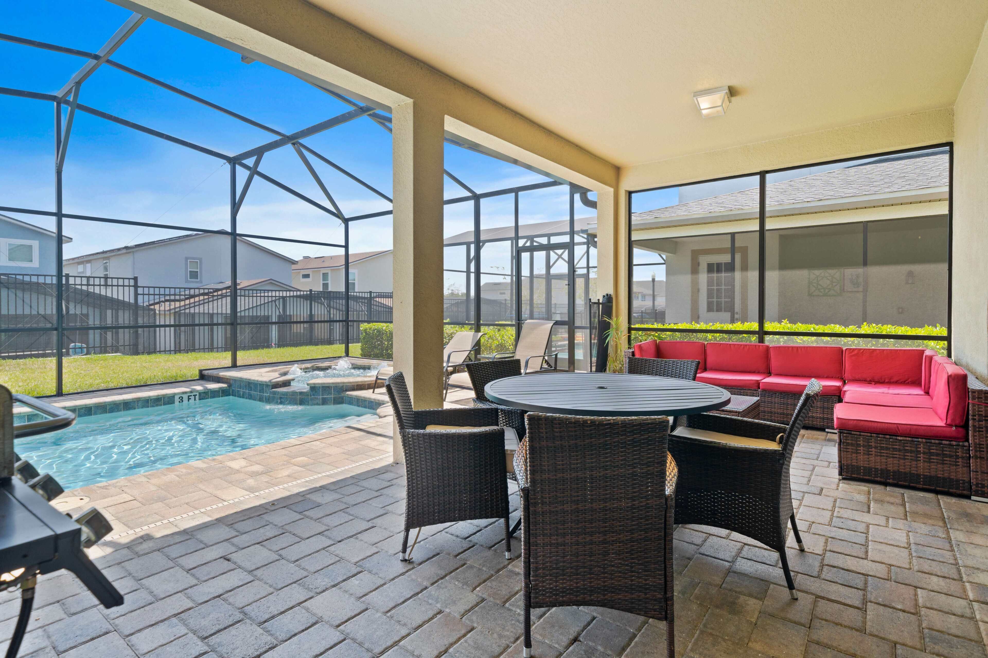 A covered outdoor area with a pool, seating, and a view of the neighborhood.