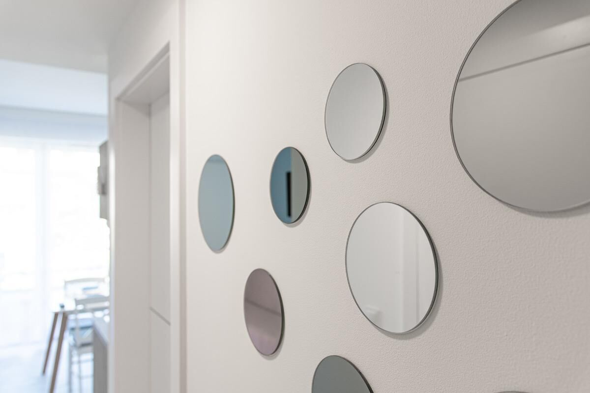 A wall with multiple round mirrors of varying sizes and colors.